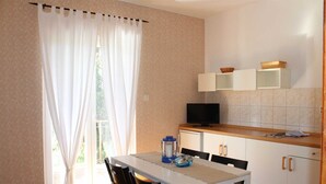 Een kleine keuken met een eettafel, een televisie en kastjes.