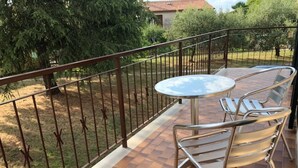 Een balkon met een metalen hekwerk, een ronde tafel en twee stoelen.