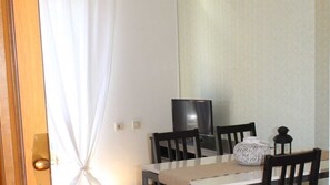 Ein Essbereich mit Tisch, Stühlen, einem Fernseher und einer Lampe.