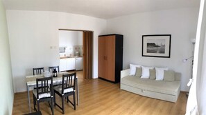 Ein kompakter Wohnbereich mit Essplatz, Küchenzeile und einer Couch.