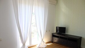 Ein Zimmer mit einer Schiebetür aus Glas, einem Flachbildfernseher auf einem dunklen Holzschrank und einer hellgrünen Wand.