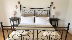 Ein Bett mit schwarzem Metallgestell, weißer Bettwäsche und zwei Nachttischen mit Lampen.