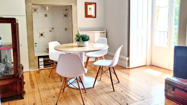 A dining area with a round table, white chairs, a potted plant, and a vintage radio. - Dear Home ★ In the Heart of Lisbon (Lisboa)