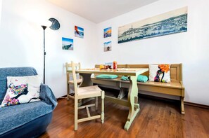 A cozy room with a wooden dining table, a sofa, and a bench. There are several paintings on the walls and a clock. - HAVANA - Apartment with Sea View (Rovinj)