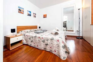 A bedroom with a wooden bed, a nightstand, a mirror, and a floor lamp. - HAVANA - Apartment with Sea View (Rovinj)