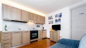 A compact kitchen with wooden cabinets, a built-in oven, and a television on the wall. - HAVANA - Apartment with Sea View (Rovinj)