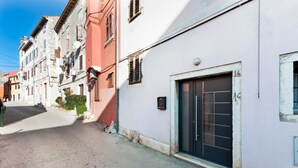 A narrow street with buildings on both sides, featuring a mix of architectural styles and a variety of window designs. - HAVANA - Apartment with Sea View (Rovinj)