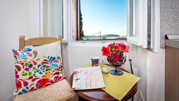 A cozy corner with a chair, a table, a book, a mug, and a vase with flowers. - HAVANA - Apartment with Sea View (Rovinj)