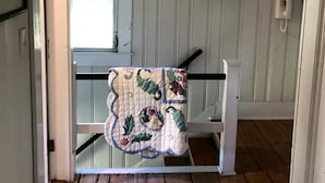 Ein Zimmer mit Holzboden, weißer Geländer und einem gemusterten Wandteppich, der am Geländer hängt.