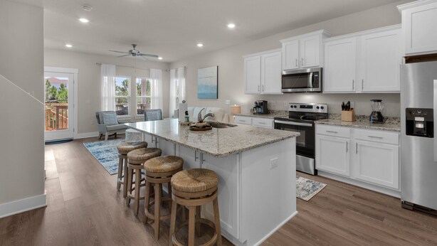 A modern kitchen with white cabinets, stainless steel appliances, and a central island with stools.