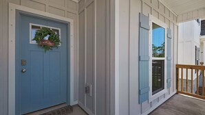 A blue door with a welcome sign and a window with shutters.