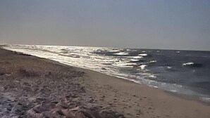 A beach with footprints and a clear sky.