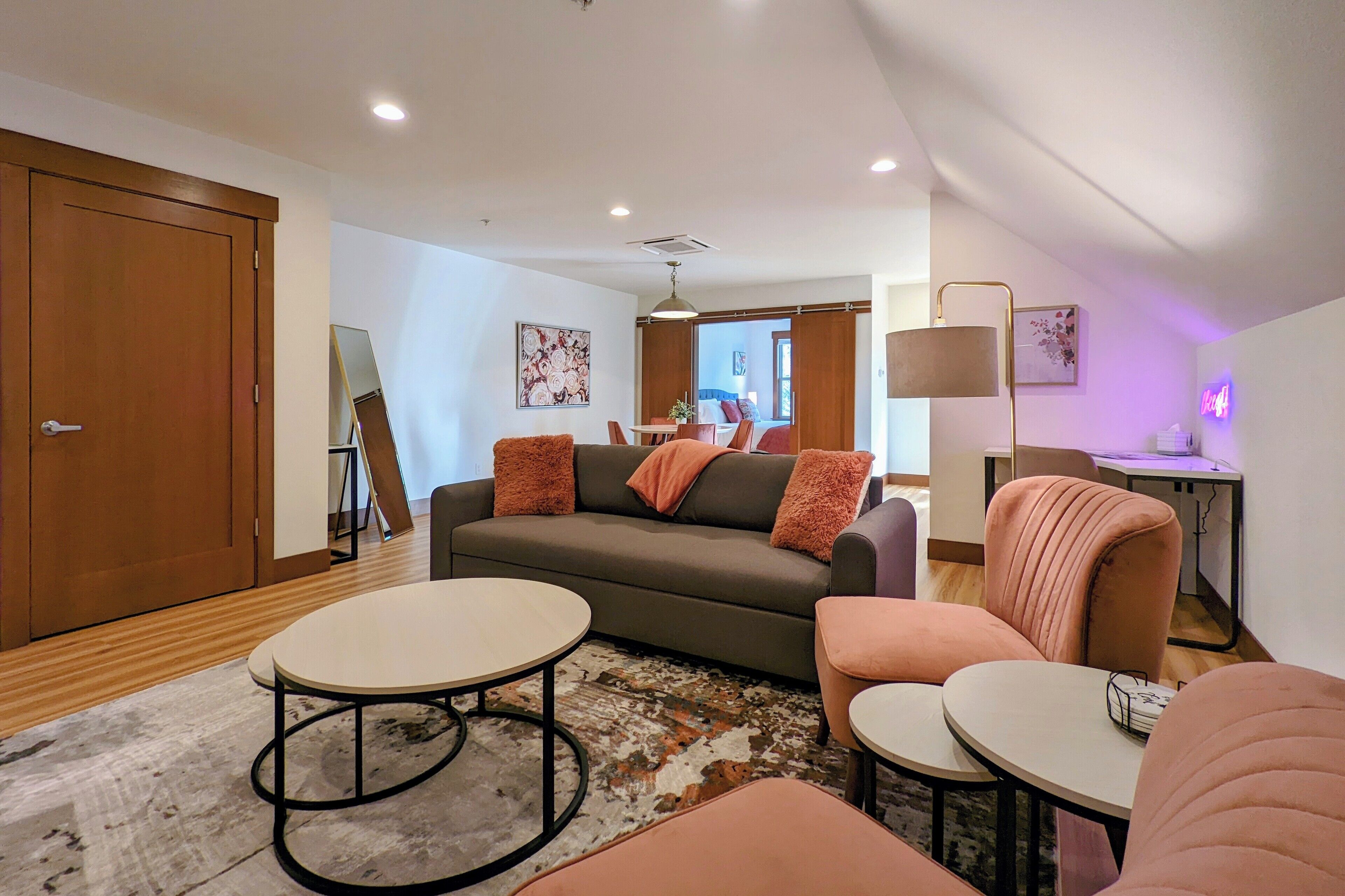 A modern living room with a sofa, two armchairs, a coffee table, and a lamp.