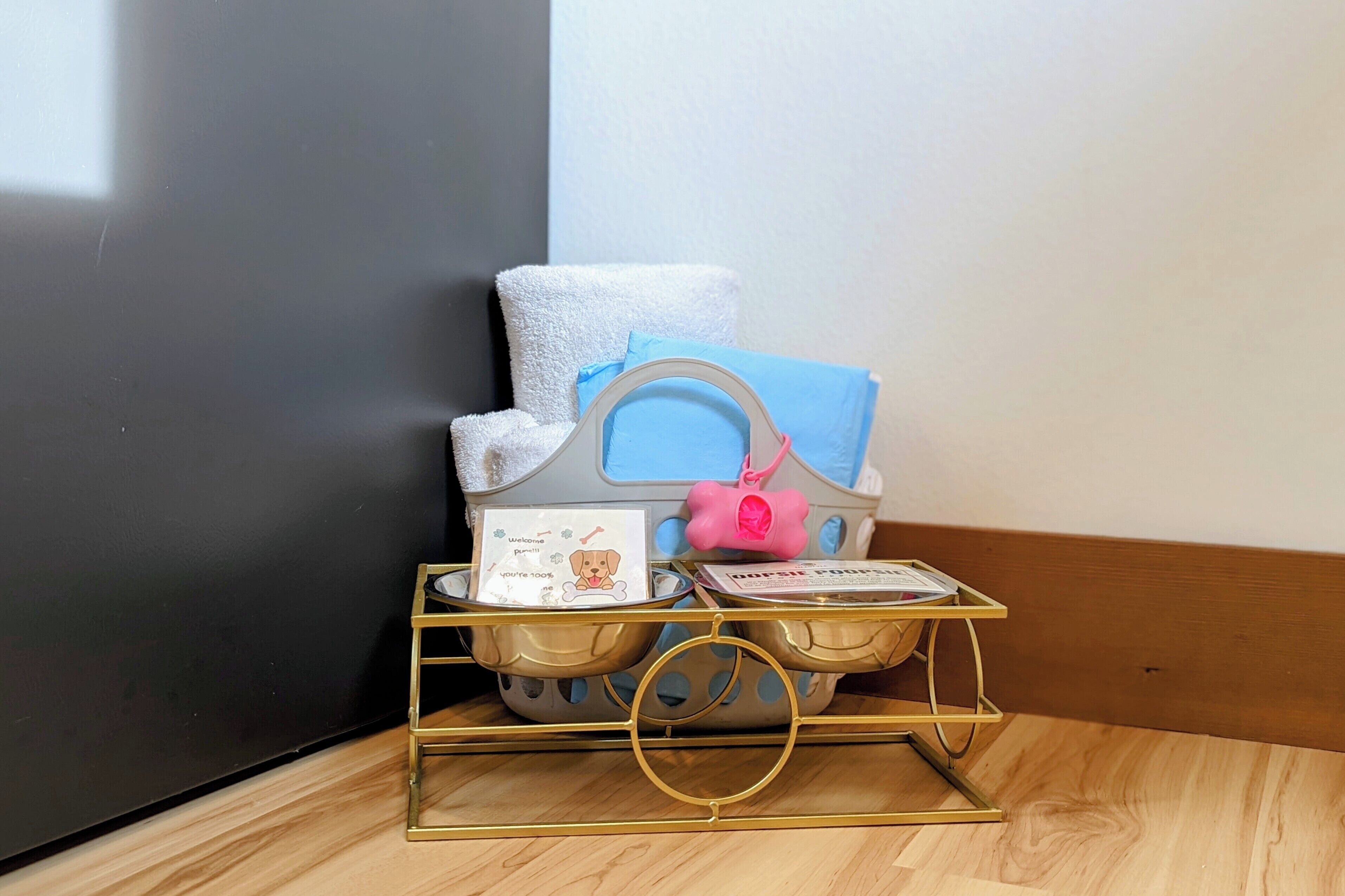A small, gold-framed, two-tiered tray with a blue towel, a pink bag, and a card on the top tier.