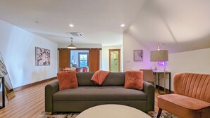 Una sala de estar moderna con un sofá gris, una mesa redonda blanca y un sillón marrón.