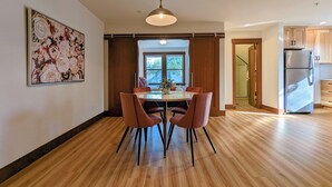 Una cocina moderna con armarios de madera, un refrigerador de acero inoxidable y un comedor con una mesa de vidrio y cuatro sillas.