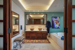 Un bagno moderno con uno specchio grande, due lavandini, una vasca e un tappeto colorato.
