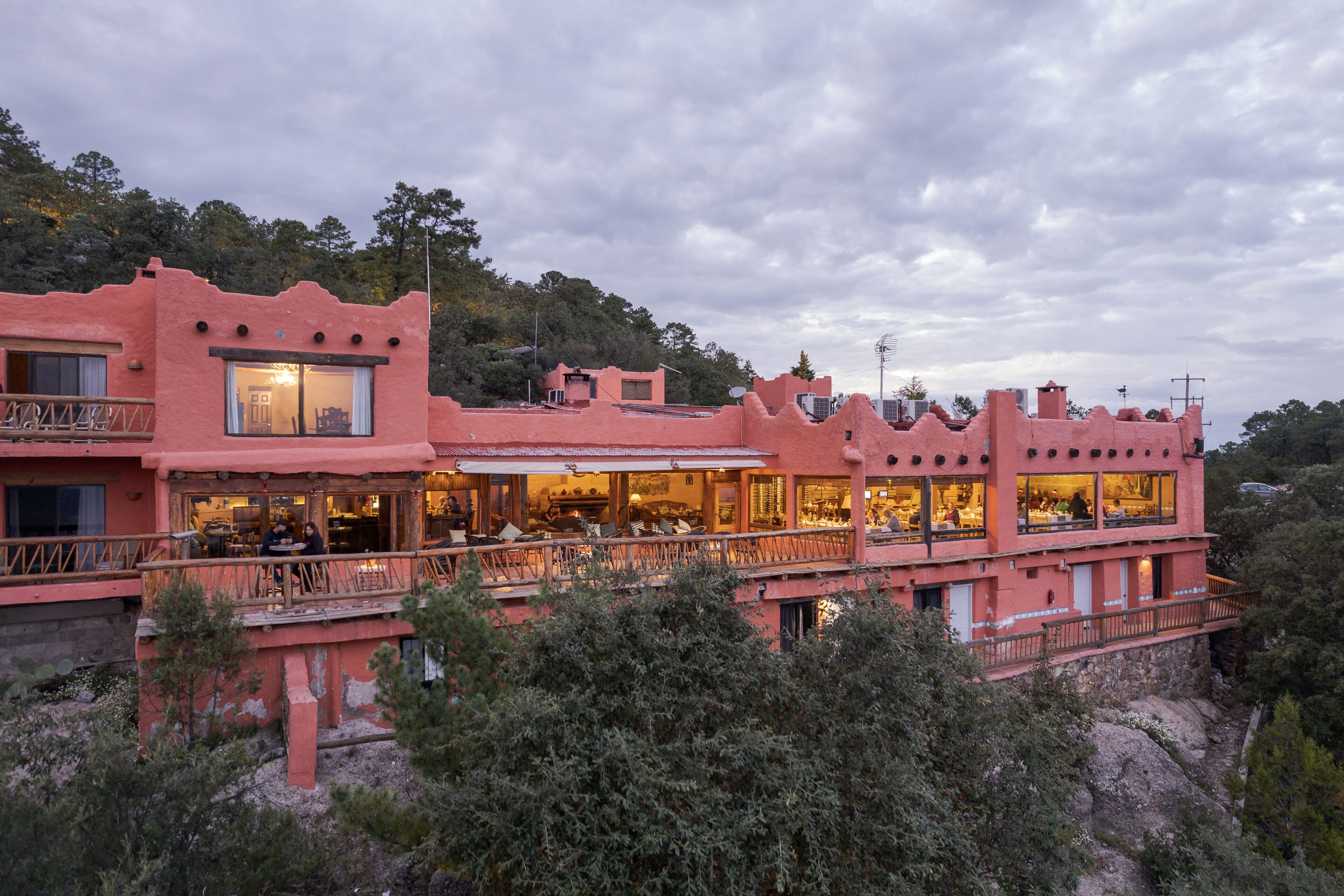 A pink building with multiple balconies and large windows, surrounded by trees.