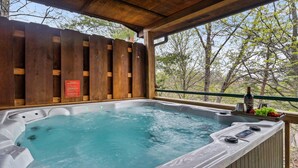 Ein Whirlpool mit Holzterrasse und Warnschild, umgeben von Bäumen.