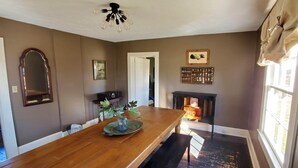 A dining area with a wooden table, a vase with flowers, a mirror, and a fireplace.