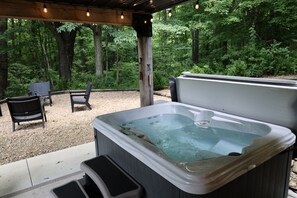 An outdoor hot tub area with seating and a wooden pergola.