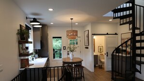 A modern kitchen with a dining area, a staircase, and a view of the outdoors.