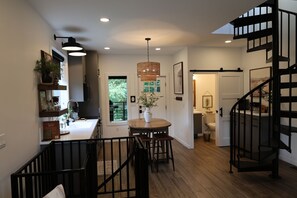 A modern kitchen with a dining area, a staircase, and a view of the outdoors.