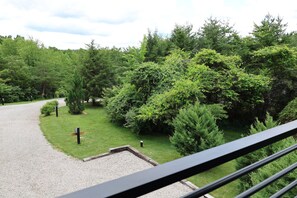 A gravel path leading through a lush green area with dense trees and a wooden bench. - Parker's Point by Creative Cabins (Logan)