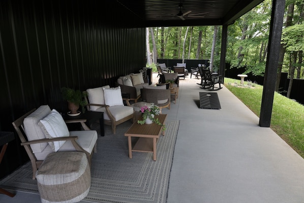 An outdoor covered patio with seating, a table, and a potted plant.