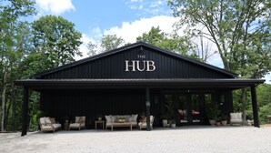 A black building with 'The HUB' sign, covered outdoor seating, and potted plants. - Parker's Point by Creative Cabins (Logan)