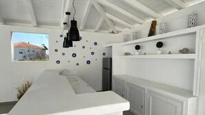 Cocina moderna con una isla blanca, iluminación colgante y vistas al exterior.