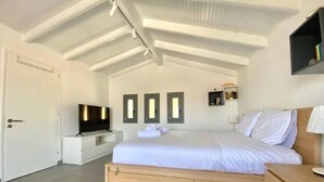 Un dormitorio moderno con una cama grande, un televisor y un aparador de madera.