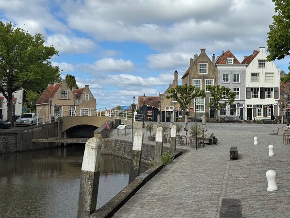 A canal with a stone bridge, historic buildings, and outdoor seating along the water. - Beautiful Detached Holiday Home in Ouddorp aan Zee (Ouddorp)