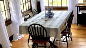 A dining area with a table set for four, surrounded by chairs, with a window view and a hanging light fixture. - 4bdrm Cottage central to year round fun w/fireplace (Weston)