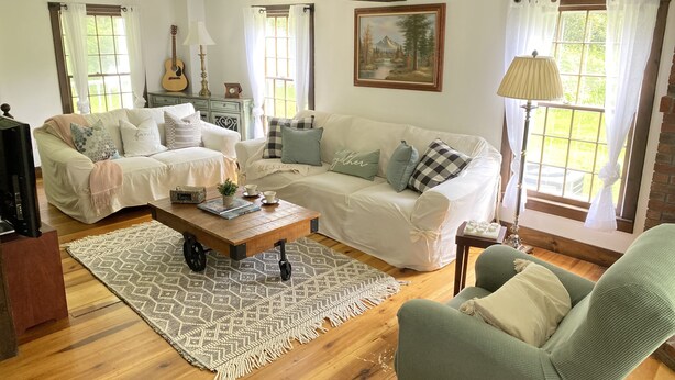 A cozy living room with a wooden floor, two sofas, a coffee table, and a painting on the wall. - 4bdrm Cottage central to year round fun w/fireplace (Weston)