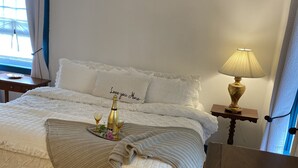 A neatly made bed with a decorative pillow, a bedside lamp, and a small table with a bottle and glass. - 4bdrm Cottage central to year round fun w/fireplace (Weston)