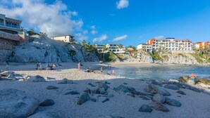A beach with rocky terrain and buildings in the background. - New! Ocean Views, Perfect Location, Great Amenities (Cabo San Lucas)