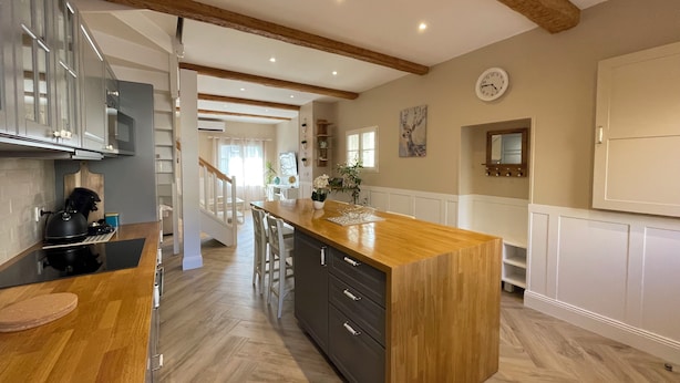 Une cuisine moderne avec un plancher en bois, un îlot central et un escalier menant à un autre niveau.