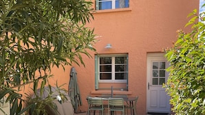 Une terrasse avec une table et des chaises, une porte et une fenêtre.