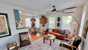 A spacious living room with a large rug, a sofa, a coffee table, and a dining area with chairs and a chandelier. - TOP FLORIDA's La Casita (Fort Myers)