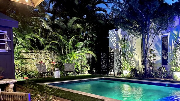 A swimming pool surrounded by lush greenery and a patio area with seating. - TOP FLORIDA's La Casita (Fort Myers)