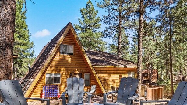 A cabin with a fire pit and Adirondack chairs in a forest setting. - Nakai Trail Vacation Rental | 4-BR A-Frame in Kachina Village, Flagstaff | Loft • Firepit  • Game Rm • Sauna • New Bathroom (Flagstaff)