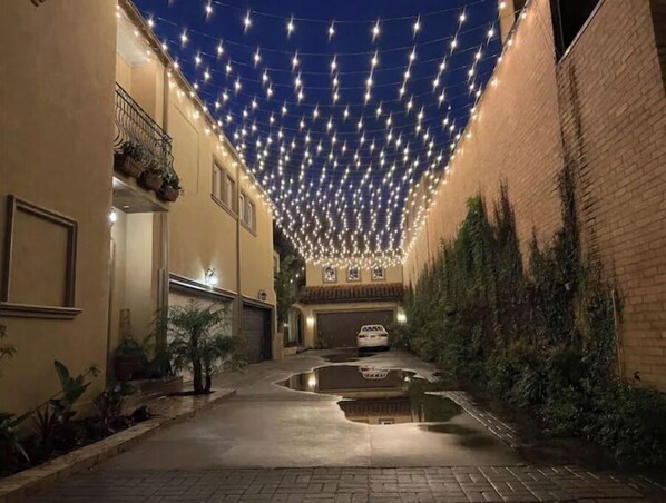 Stroll through this serene courtyard, lined with a curved walkway and surrounded by lush greenery and twinkling lights.