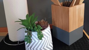 A kitchen area with a roll of paper towels, a potted plant, and a wooden utensil holder. - The East Loft at Dartmouth Avenue *New 1 Bed-Apt. (Providence)