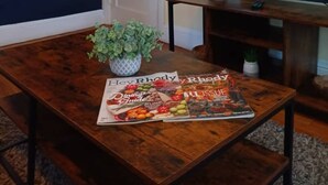 A dining table with a magazine, a potted plant, and a television on a stand. - The East Loft at Dartmouth Avenue *New 1 Bed-Apt. (Providence)