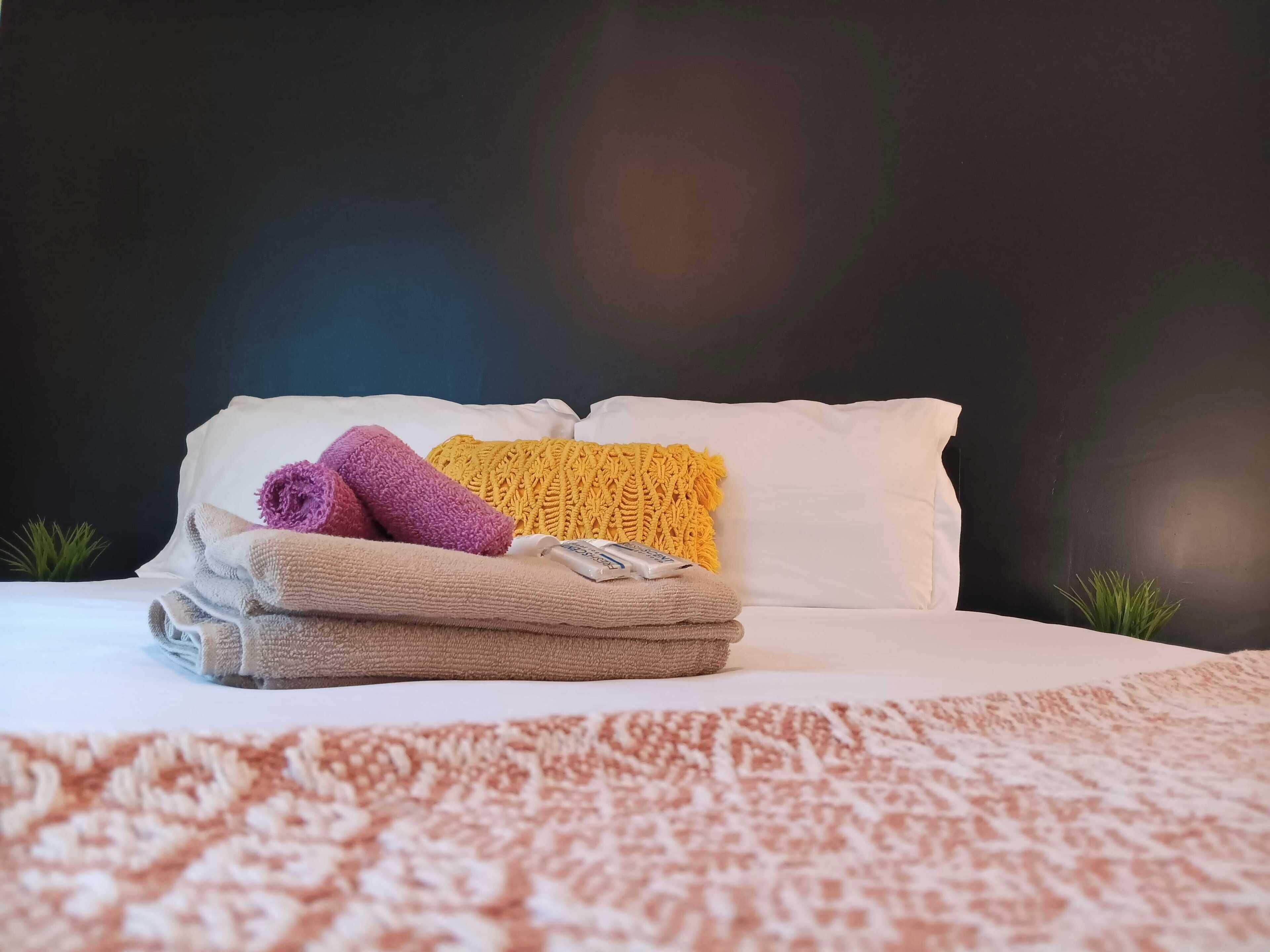 A neatly made bed with white pillows and a folded beige blanket.