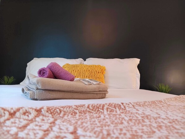 A neatly made bed with white pillows and a folded beige blanket.