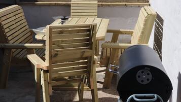 A wooden outdoor dining set with a grill.