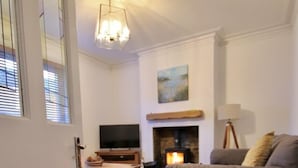 Una sala de estar con chimenea, un sofá, un televisor y piso de madera.