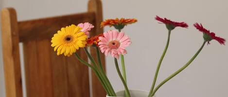 A white vase with blue fish patterns containing pink and yellow flowers.